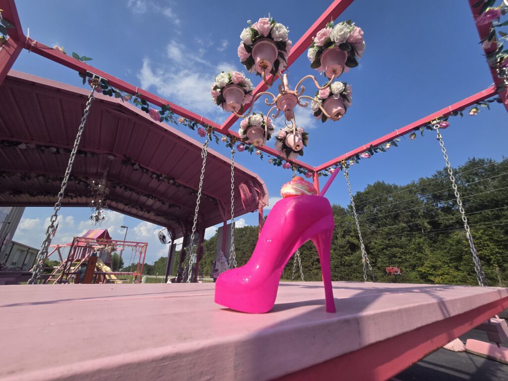 Pink high heel cup display at Junie B’s Snowcones outdoor storefront with floral chandeliers