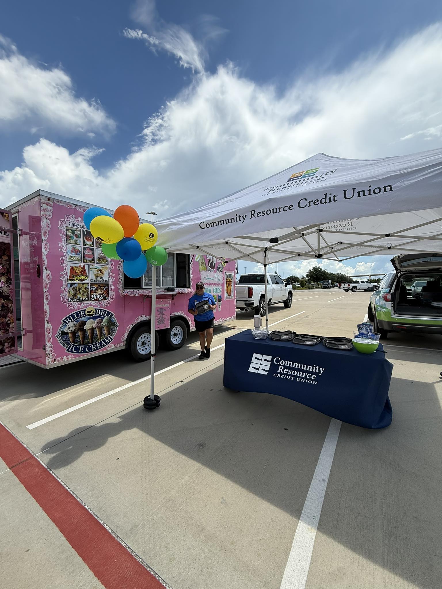 Junie B’s Snowcones pink trailer stand at a community event with balloons and canopy
